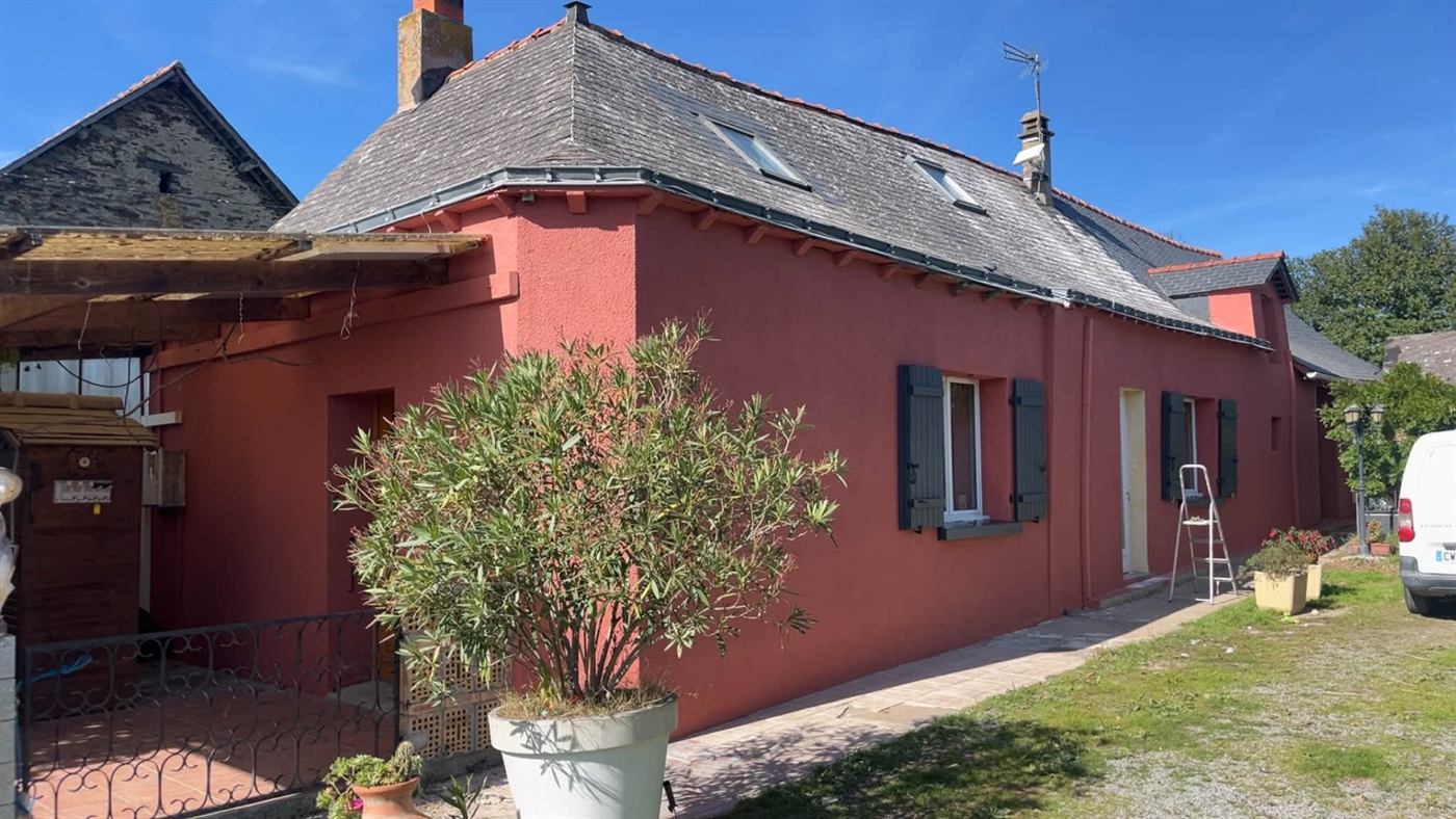 Après : la même maison, façade repeinte en rouge et toiture nettoyée