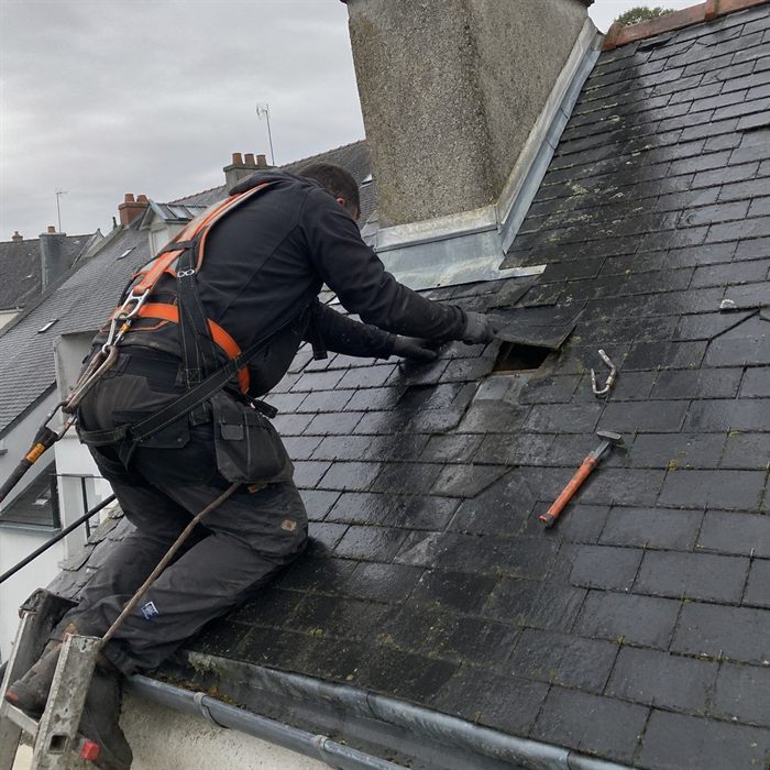 Couvreur harnaché au travail sur une toiture en ardoise