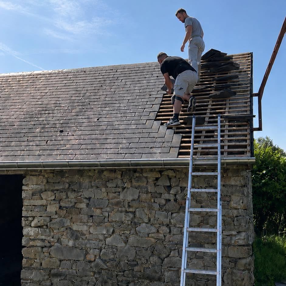 Deux couvreurs sur une charpente de toiture, échelle appuyée contre le mur